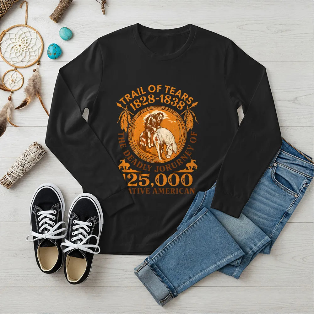 A black long-sleeve t-shirt with the "Trail of Tears" commemorative design, paired with blue jeans and black sneakers on a wooden background.