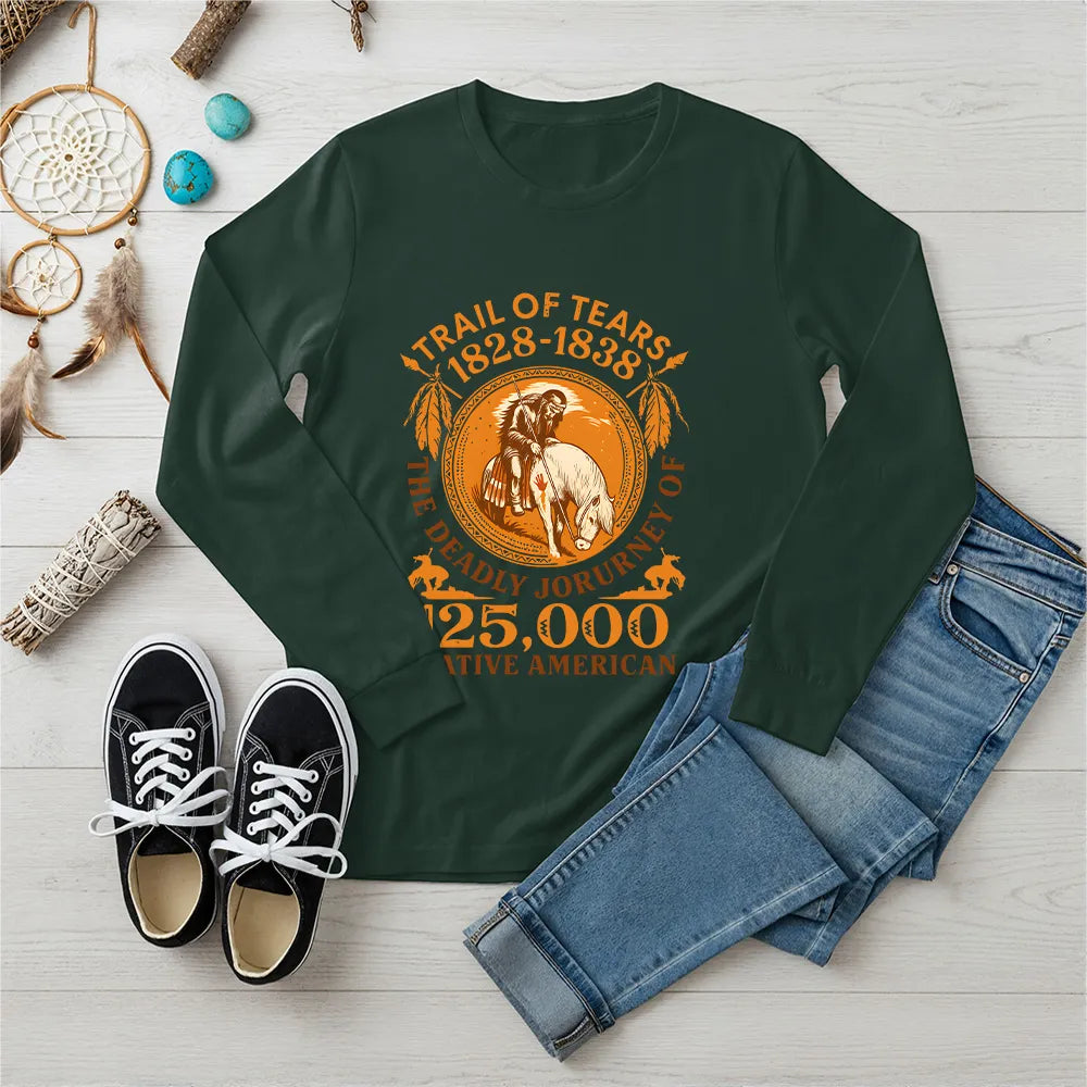 A forest green long-sleeve t-shirt with an indigenous-inspired "Trail of Tears" motif, displayed with jeans and black sneakers.