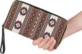 A hand holding the brown patterned wristlet wallet against a white background, showcasing its size and detailed tribal-inspired print.